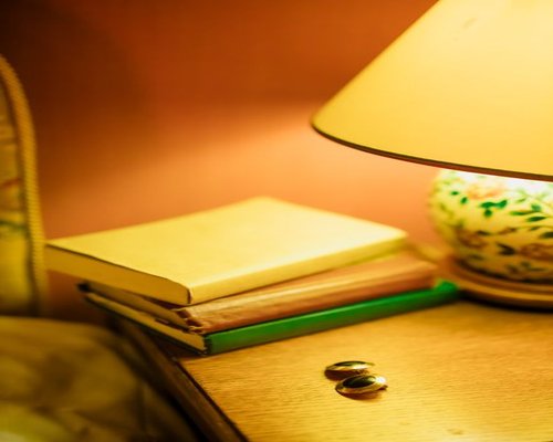 A cozy bedroom corner featuring a night lamp casting warm ambient lighting over a closed book